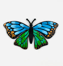 Butterfly-shaped magnet with blue and green wings on a white background