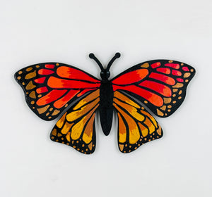 Butterfly-shaped magnet with red, orange, and black colors on a white background