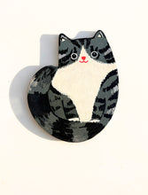 Cat-shaped magnet with black and white design on a white background