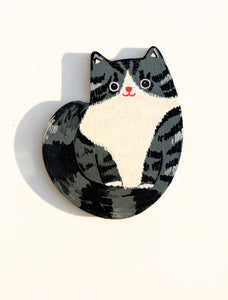 Cat-shaped magnet with black and white design on a white background